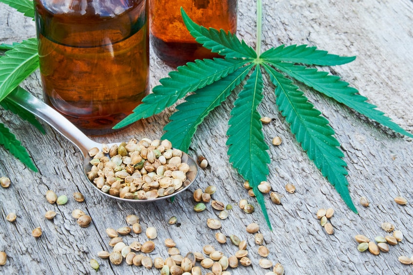 hemp leaves on wooden background, seeds, cannabis oil extracts in jars